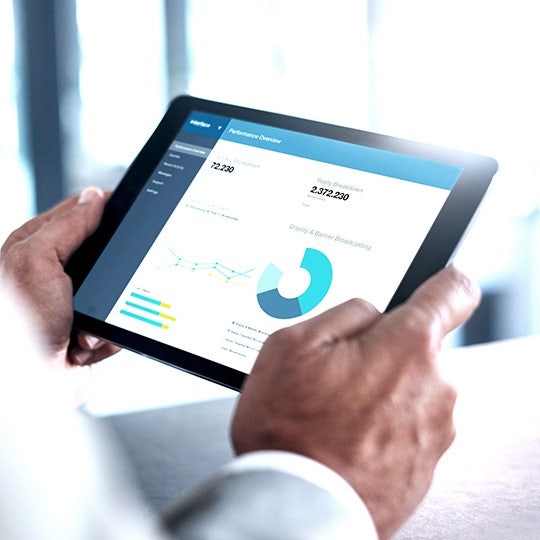 close up of hands holding a tablet showing a graph