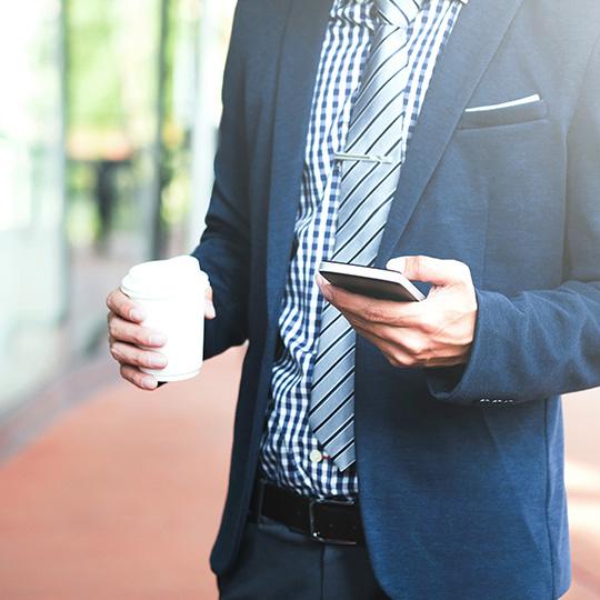 Varför utskrifter är fortsatt viktiga businessman holding a coffee and mobile phone
